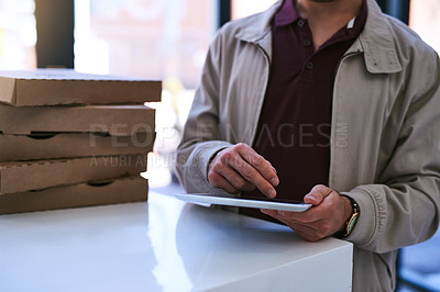 Buy stock photo Cropped shot of a man using a digital tablet while making a pizza delivery