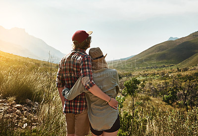 Buy stock photo Rearview shot of a young couple admiring a mountainous view in nature
