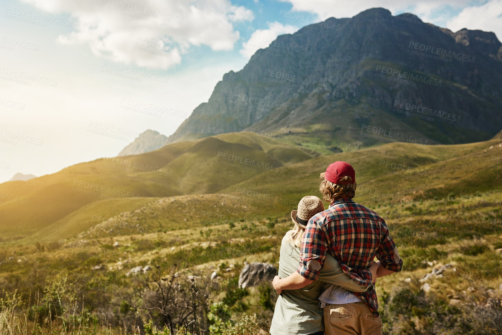 Buy stock photo Rearview shot of a young couple admiring a mountainous view in nature