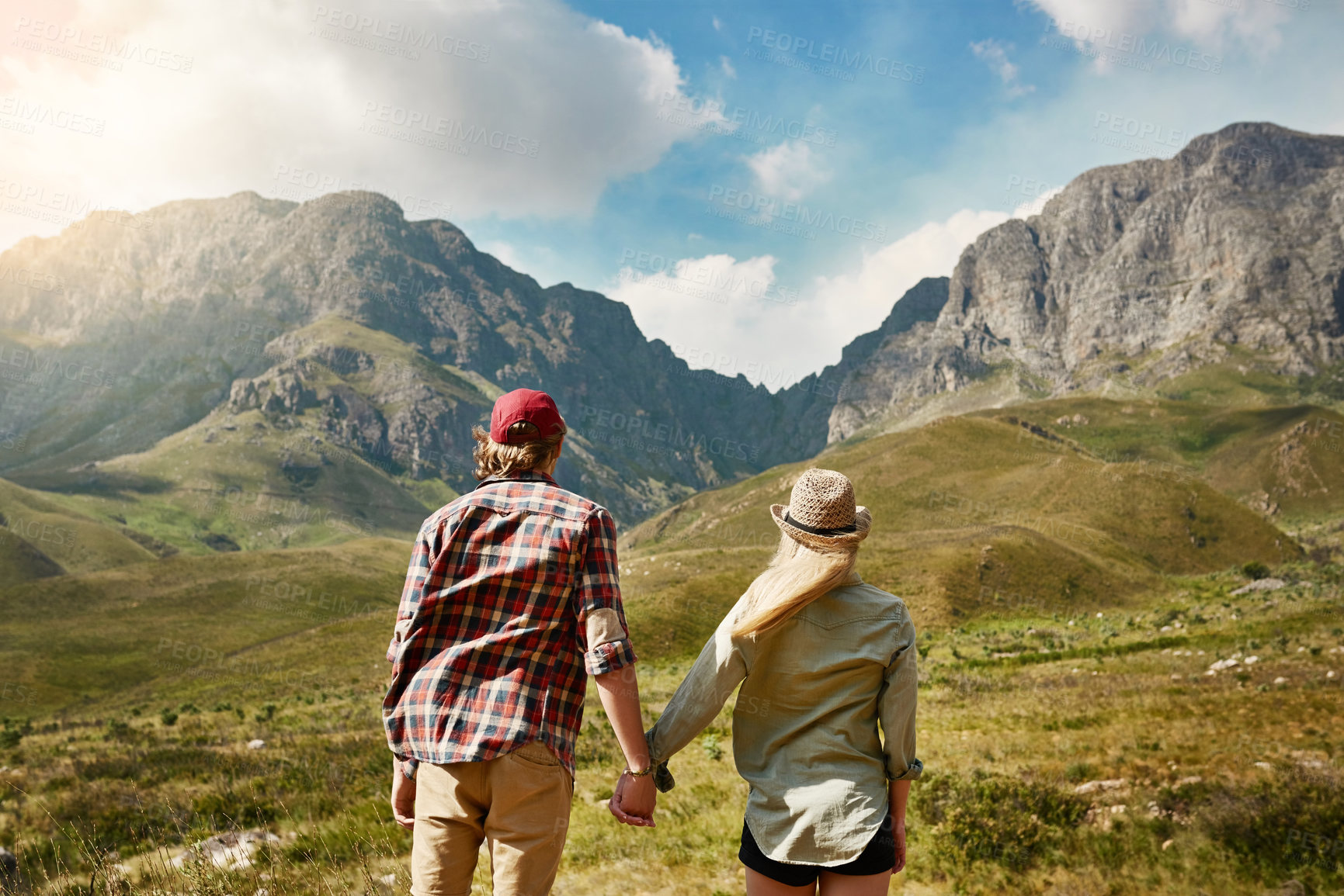 Buy stock photo Rearview shot of a young couple admiring a mountainous view in nature