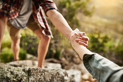 Buy stock photo Cropped shot of hikers helping each other climb up a rock in nature