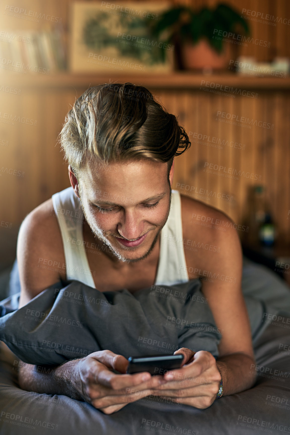 Buy stock photo Relax, happy and man on bed with phone for online chatting, communication and networking. Morning, home and person typing on smartphone for social media, website blog and mobile app in bedroom