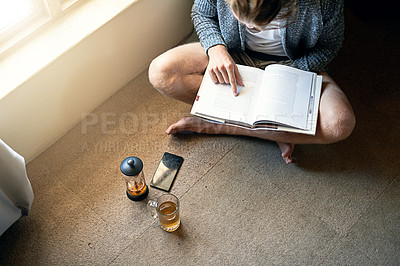 Buy stock photo High angle shot of an unidentifiable young man reading a book at home