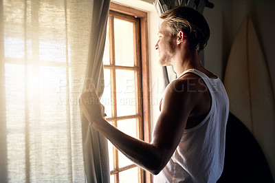 Buy stock photo Cropped shot of a young man looking out the window at home