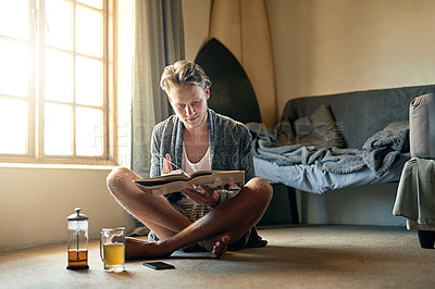 Buy stock photo Shot of a young man reading a book at home