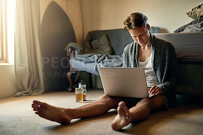 Buy stock photo Shot of a young man using his laptop at home