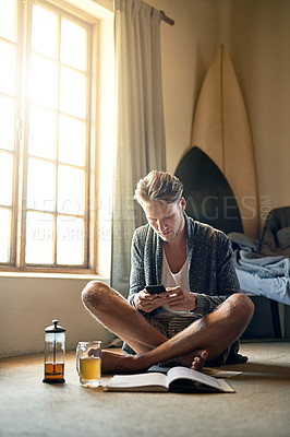 Buy stock photo Shot of a young man texting on his cellphone at home