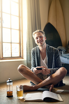 Buy stock photo Portrait of a young man texting on his cellphone at home