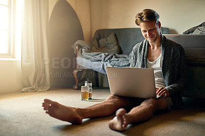 Buy stock photo Shot of a young man using his laptop at home