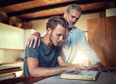 Buy stock photo Shot of a father and son doing Bible study together at home