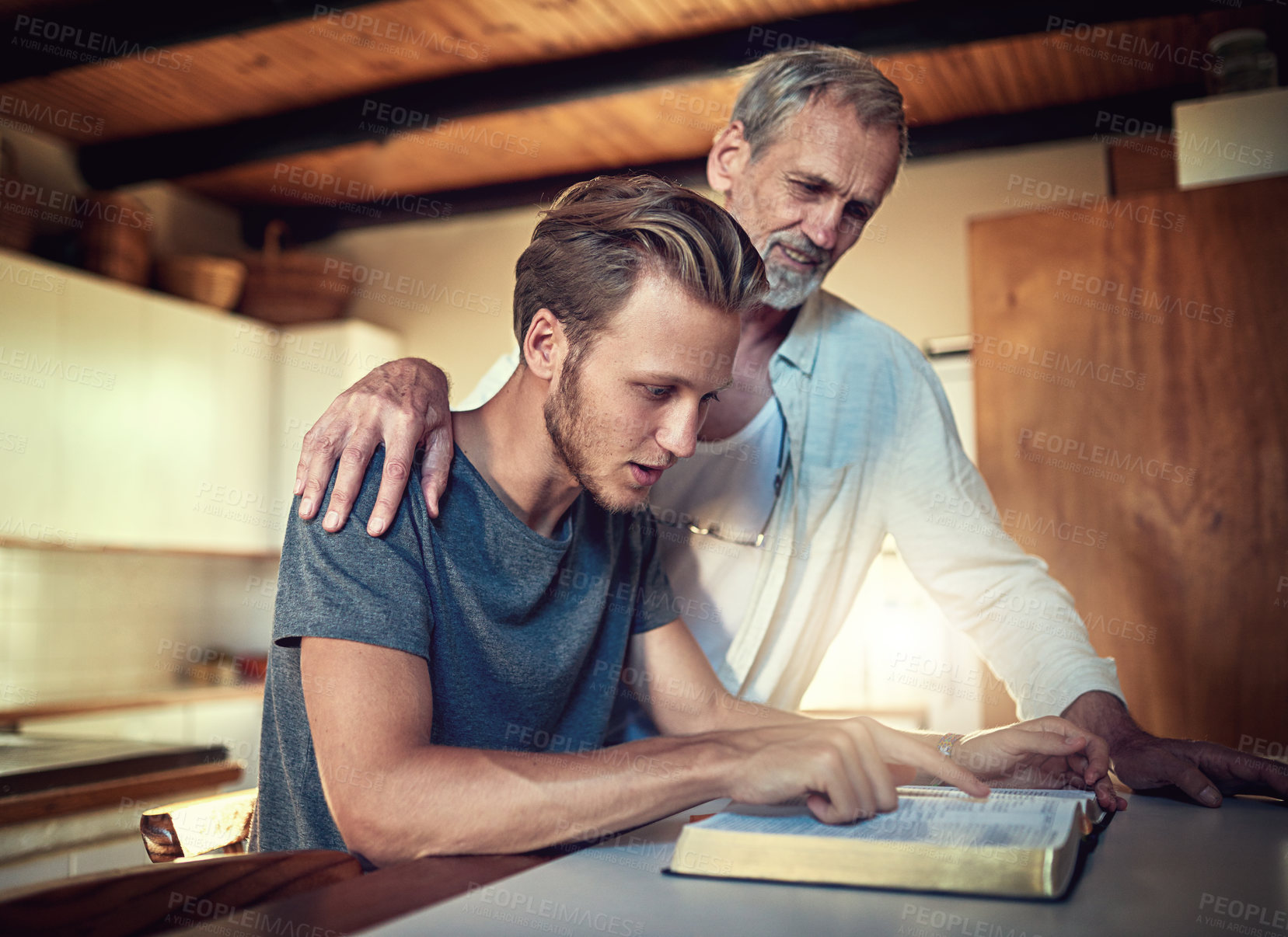 Buy stock photo Shot of a father and son doing Bible study together at home