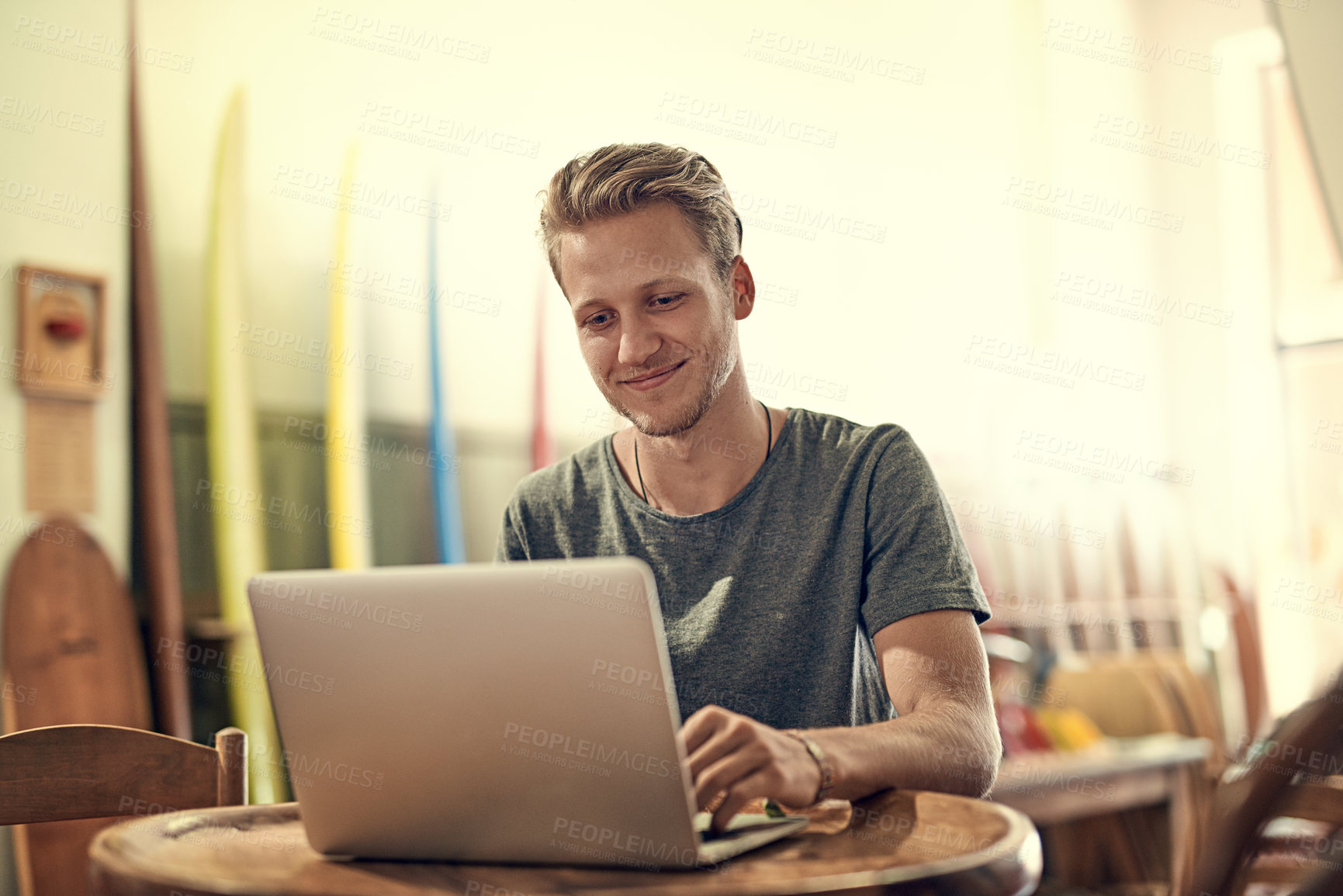 Buy stock photo Shot of a happy young man using his laptop while relaxing at home