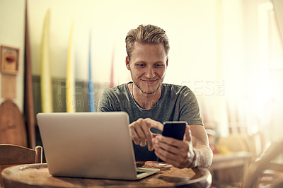 Buy stock photo Shot of a happy young man using his laptop while relaxing at home