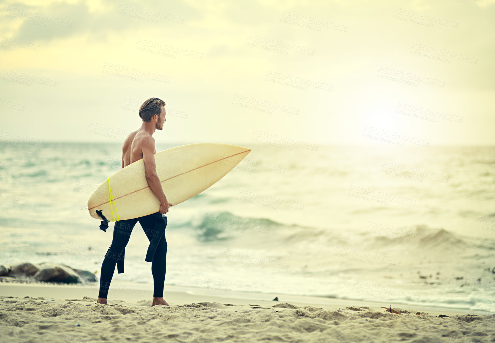 Buy stock photo Shot of a shirtless young surfer walking into the ocean with his surfboard under his arm