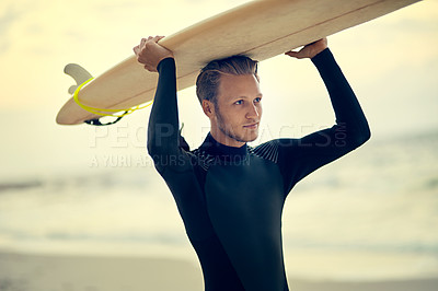Buy stock photo Shot of a laid-back young surfer watching the waves while holding his surfboard at the beach
