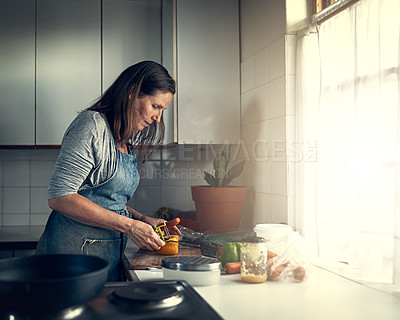 Buy stock photo Shot of a mature woman preparing a meal in her kitchen at home