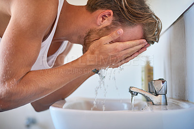 Buy stock photo Cropped shot of a young man washing his face in the bathroom