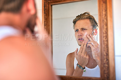 Buy stock photo Cropped shot of an attractive young man examining his skin in the bathroom mirror
