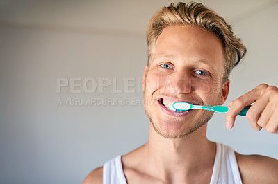 Buy stock photo Cropped shot of a young man brushing his teeth in the bathroom