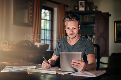 Buy stock photo Shot of a diligent young student using his tablet to do a homework assignment at home