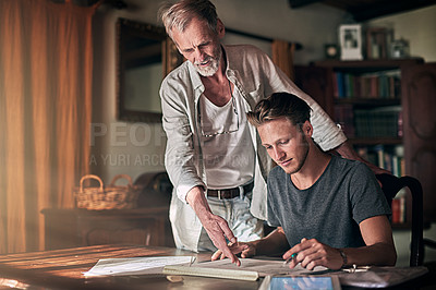 Buy stock photo Shot of a father and his son working on a design for their family business at home