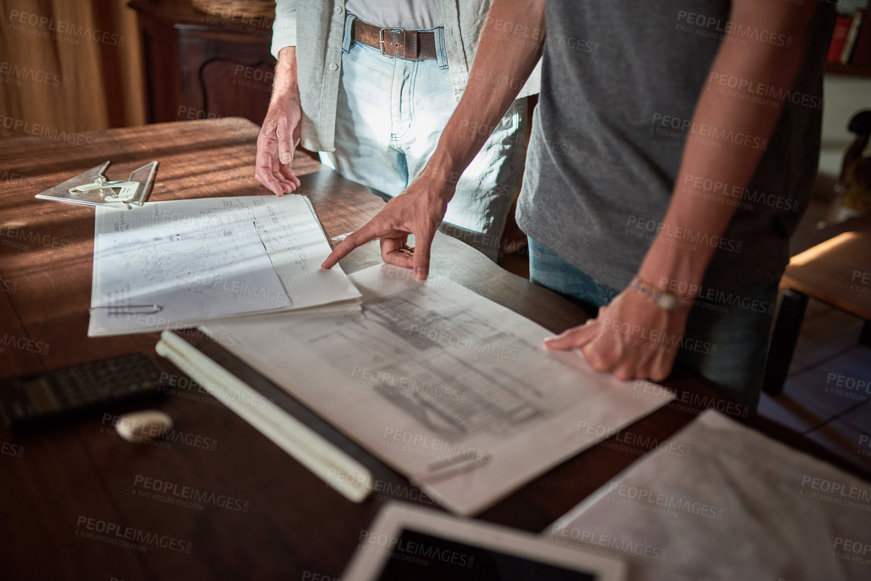 Buy stock photo Shot of an unidentifiable father and his son working on a design for their family business at home