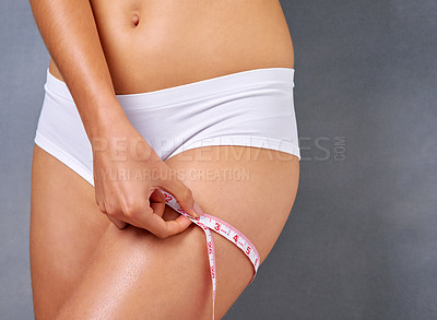 Buy stock photo Studio shot of a woman measuring her thigh against a grey background