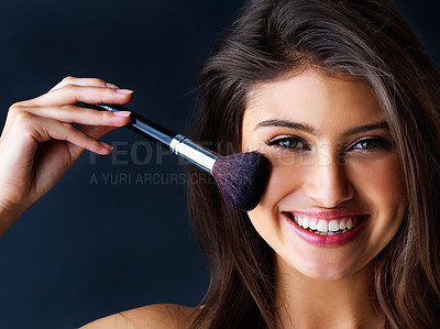 Buy stock photo Portrait of a gorgeous young woman with a makeup brush against a dark background