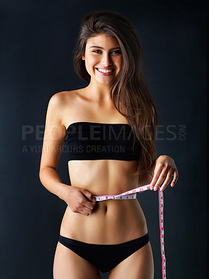 Buy stock photo Portrait, woman and measure stomach in studio, underwear and check for weight loss with diet balance. Smile, girl and tape for abdomen goal, target and body progress results on blue background
