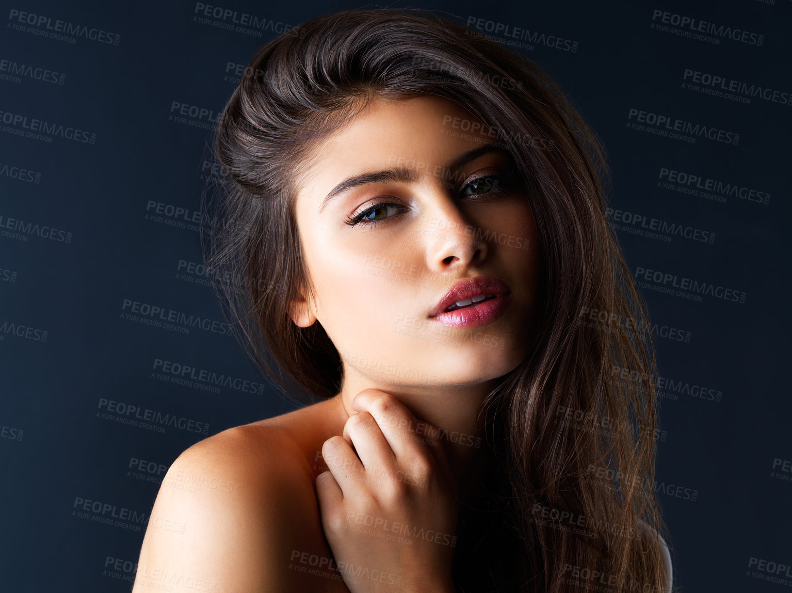 Buy stock photo Cropped portrait of a gorgeous young woman posing against a dark background