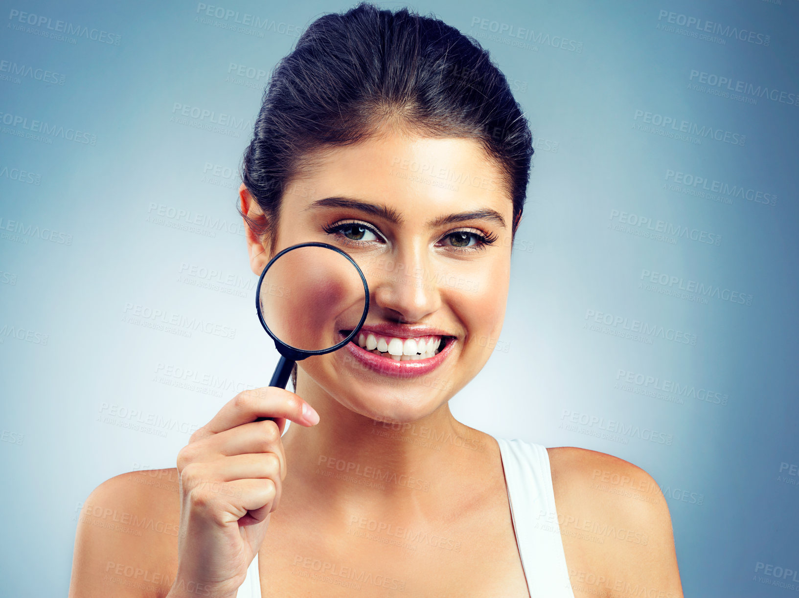 Buy stock photo Studio portrait of an attractive young woman holding a magnifying glass