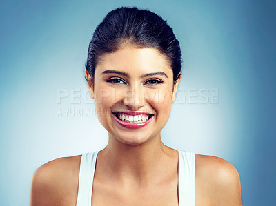 Buy stock photo Studio portrait of an attractive young woman standing against a blue background