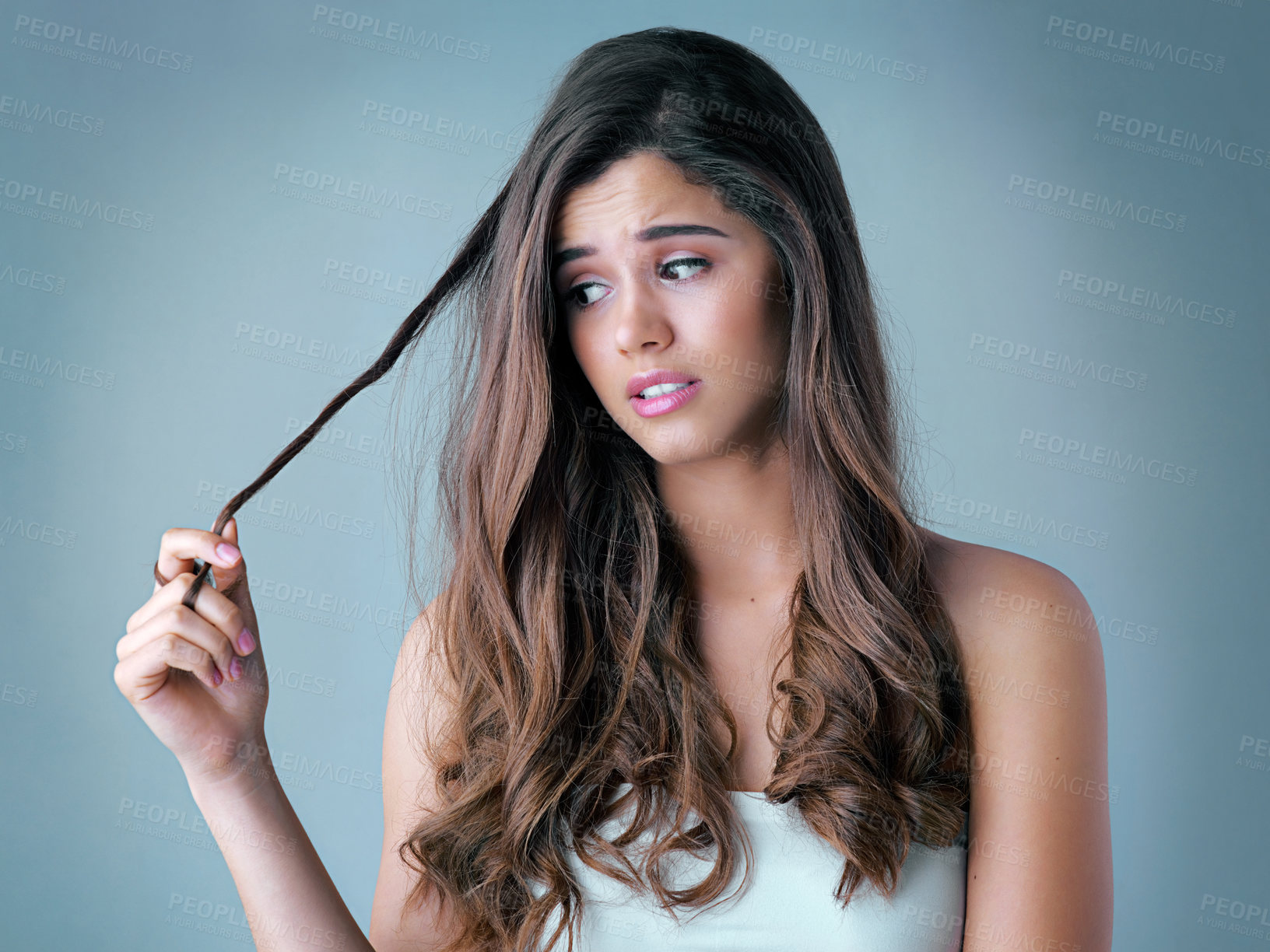 Buy stock photo Treatment, damage and woman in studio with hair care, cosmetic results or checking split ends. Heat, texture and frustrated girl with hairstyle crisis, keratin therapy and thinking on blue background