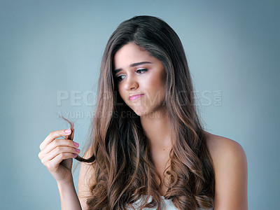 Buy stock photo Studio shot of a beautiful young woman looking at her split ends