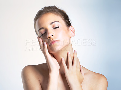 Buy stock photo Studio shot of a beautiful young woman with her eyes closed touching her neck and face