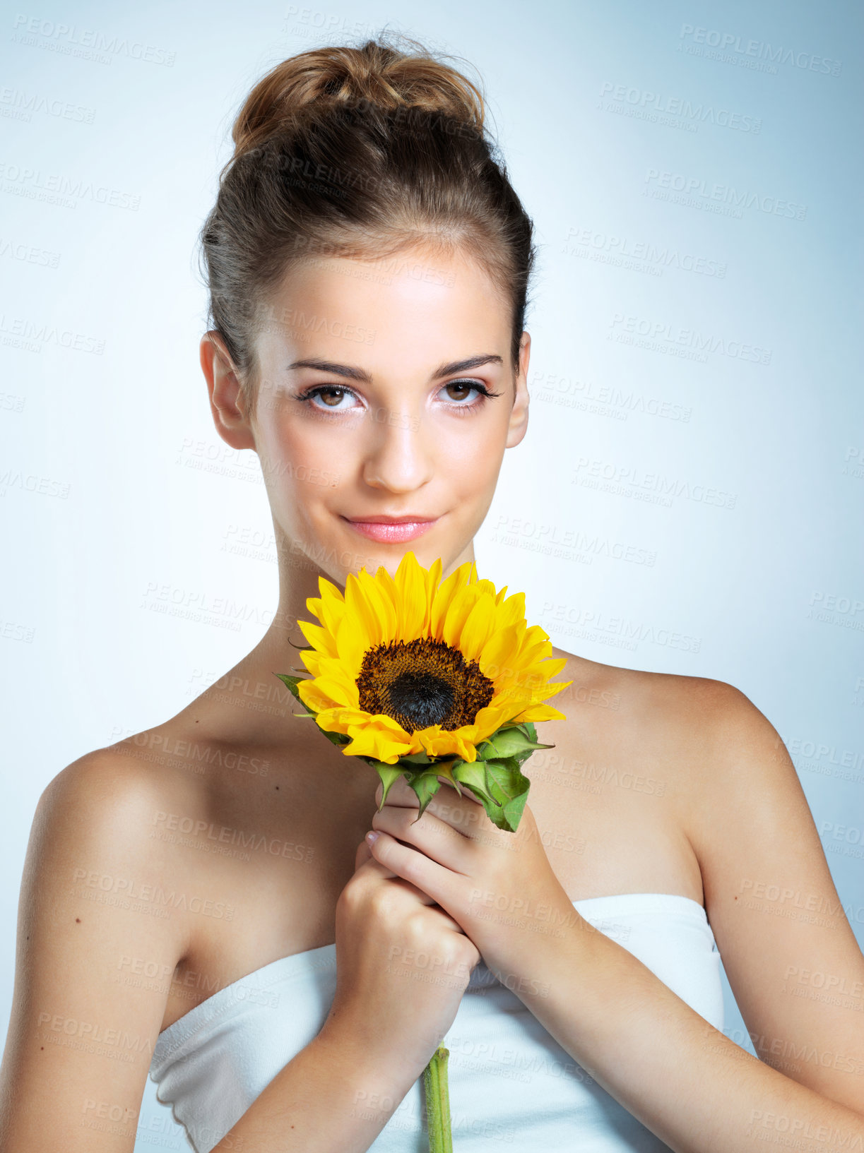 Buy stock photo Studio portrait of a beautiful young woman holding a sunflower