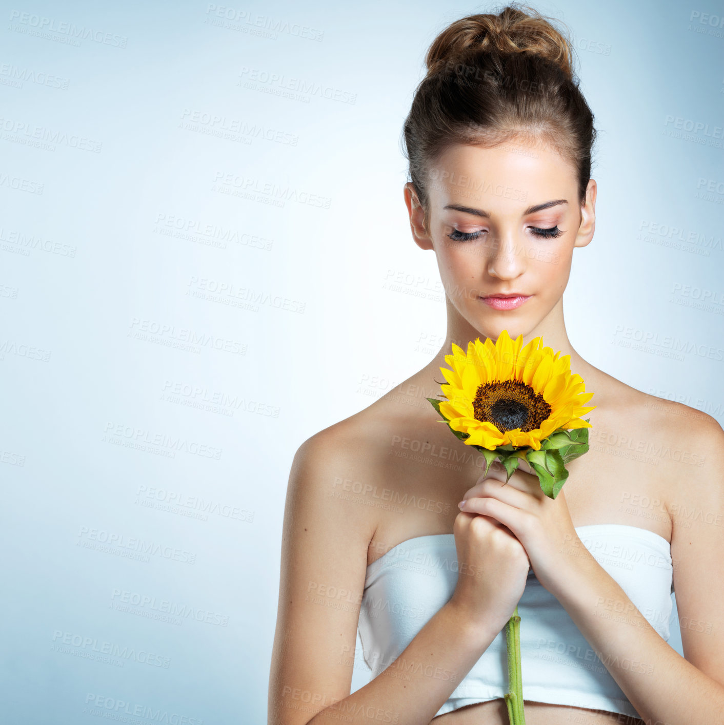 Buy stock photo Sunflower, makeup and woman in studio with mockup space for natural, organic and facial makeover. Glow, cosmetics and female person with yellow floral plant for beauty face routine by blue background