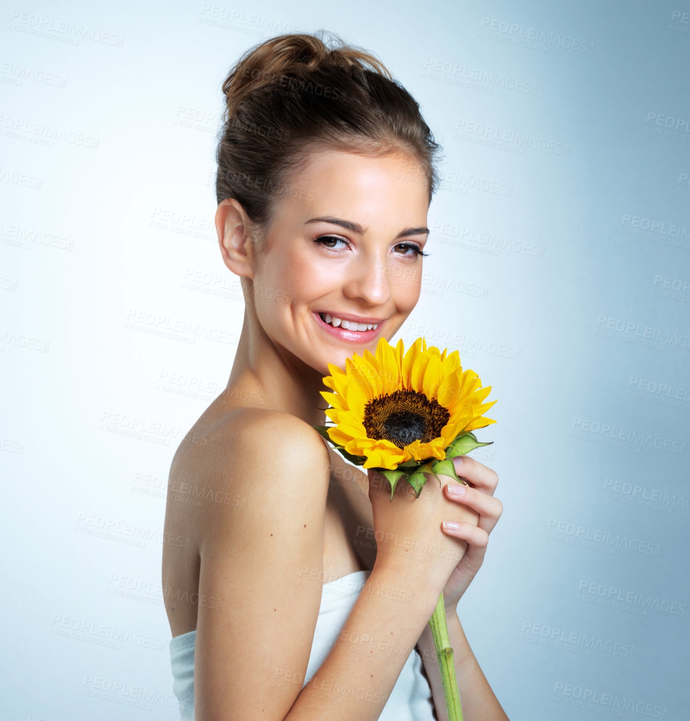 Buy stock photo Sunflower, cosmetics and portrait of woman in studio with natural, organic and beauty facial makeover. Glow, makeup and person with yellow floral plant for cosmetology face routine by blue background