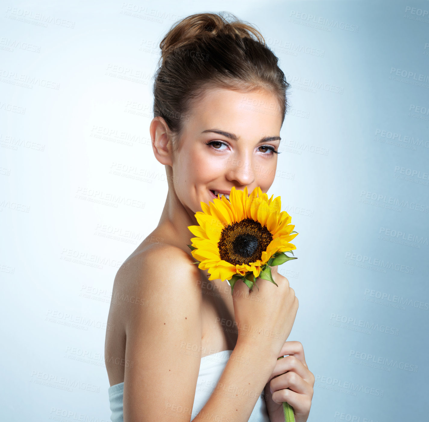 Buy stock photo Studio portrait of a beautiful young woman holding a sunflower