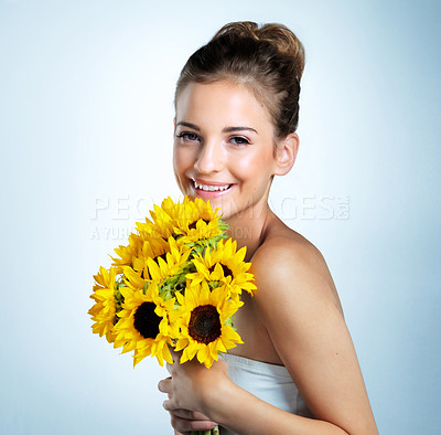 Buy stock photo Studio portrait of a beautiful young woman holding a bouquet of sunflowers