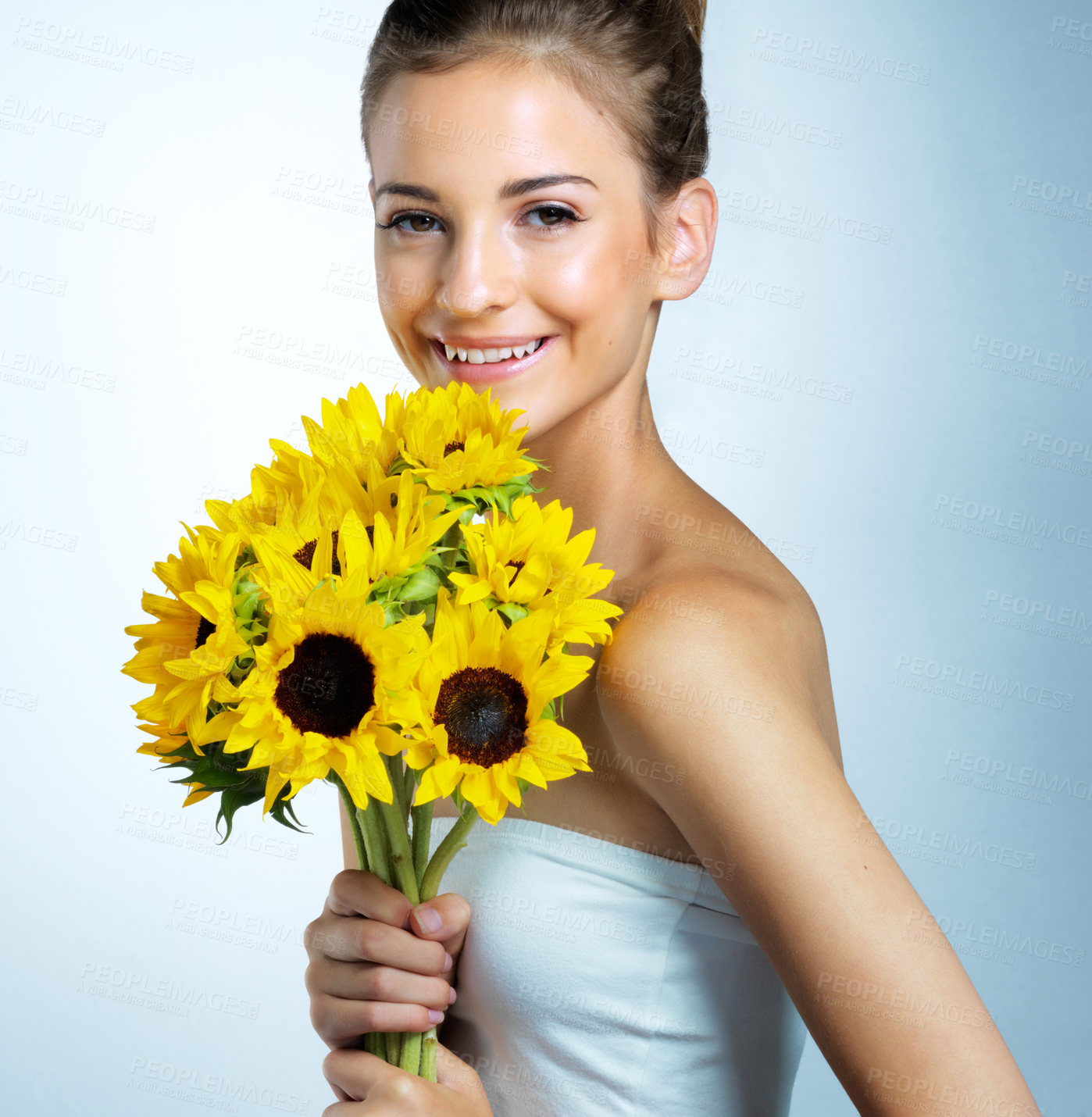 Buy stock photo Skincare, portrait and woman with bouquet of sunflowers in studio for natural, beauty and facial routine. Health, face and female person with floral plants for organic dermatology by blue background.