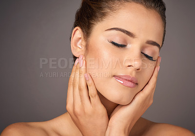 Buy stock photo Studio shot of a beautiful young woman feeling her skin against a gray background