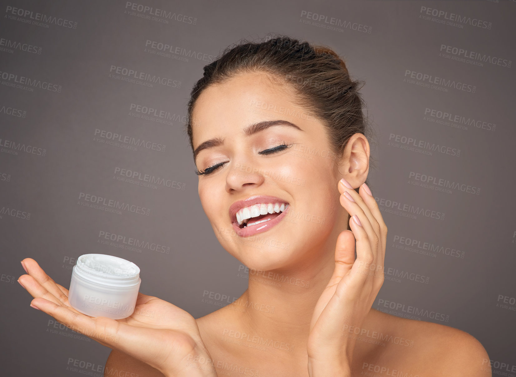 Buy stock photo Portrait of a beautiful young model  holding up a tub of skin cream in studio