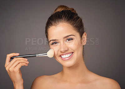 Buy stock photo Portrait of a beautiful young model applying blusher to her cheeks in studio