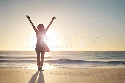 Buy stock photo Rearview shot of a woman posing with her arms outstretched at the beach