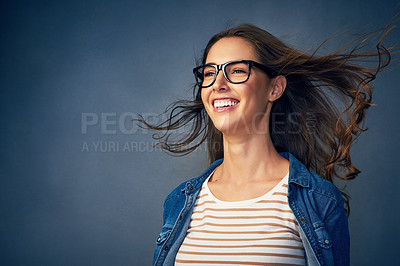 Buy stock photo Shot of a happy young woman with air being blown in her face in studio