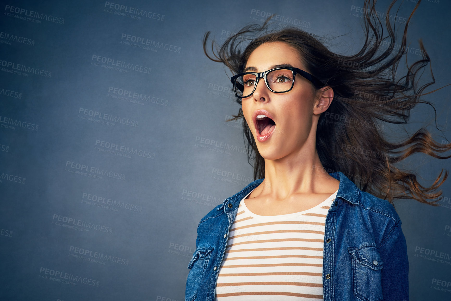 Buy stock photo Surprise, woman and glasses with wind in studio for hair blow, crazy weather and comedy for good news as winner. Shocked, female geek with eyewear for lottery giveaway, wow and blue background