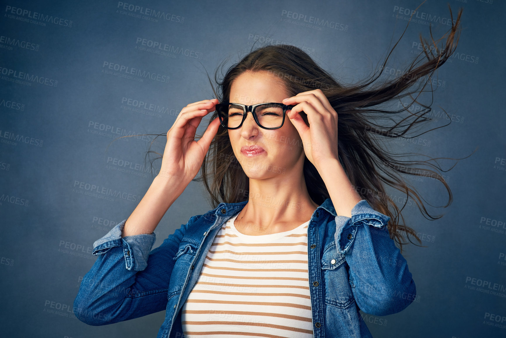 Buy stock photo Surprise, woman and glasses with wind in studio for hair blow, crazy weather and comedy for good news as winner. Shocked, female geek with eyewear for lottery giveaway, wow and blue background