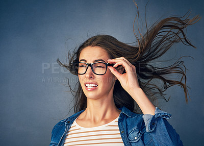 Buy stock photo Shot of a happy young woman with air being blown in her face in studio