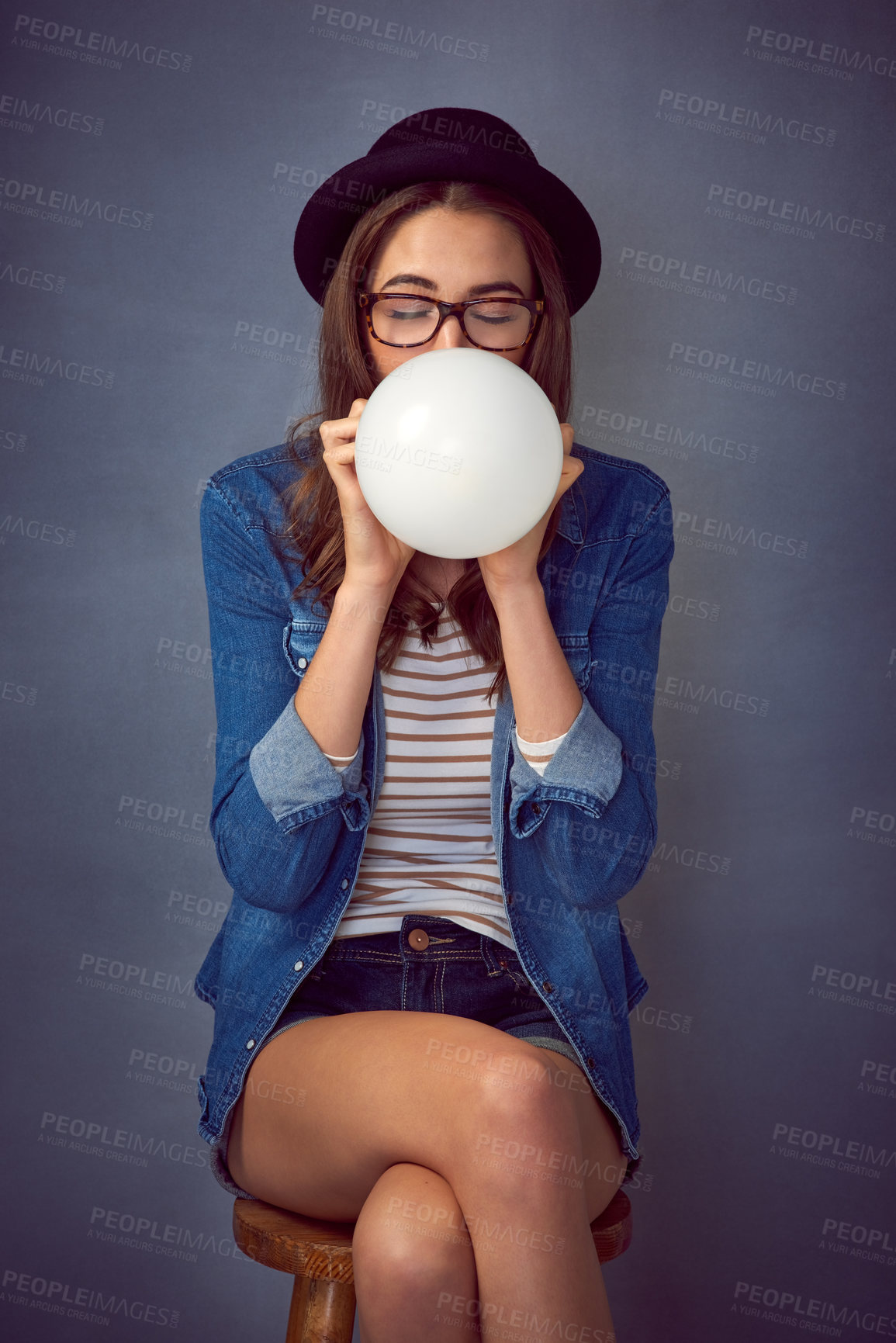 Buy stock photo Relax, balloon and woman with blowing in studio for enjoyment, fun or celebration on blue background. Party planner, glasses and person with inflatable decoration for fashion, event or setup in Paris